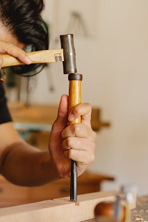 Photo by Ono  Kosuki: https://www.pexels.com/photo/crop-man-carving-wooden-plank-with-chisel-and-hammer-in-workshop-5974411/